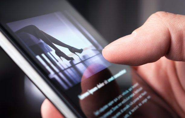 一个男人正在看一张穿着高跟鞋的女人拿着智能手机的照片。图片下载