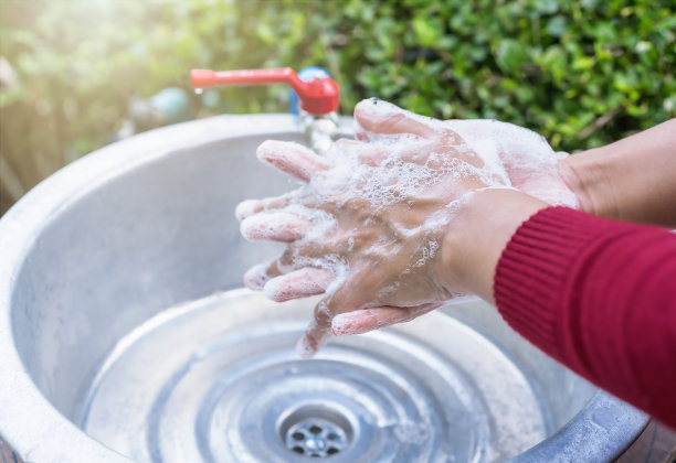 年轻女子的近距离洗手水槽与自来水在家里舒适的户外花园。有选择地集中洗手，防止细菌传播。卫生、医疗保健的概念。图片下载
