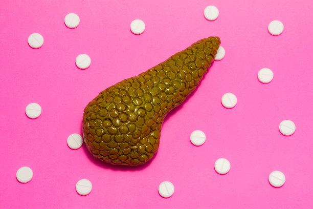 粉红色背景的人体或动物胰腺的解剖逼真的图形或模型，周围是白色的药片或药丸，以圆点装饰排列。用于医学的照片图片下载