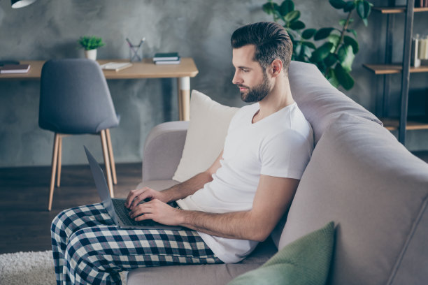 聪明酷的老板侧面照片男人坐在沙发上穿着睡衣睡衣装工作远程笔记本电脑在室内与代理人投资者进行在线交流图片下载