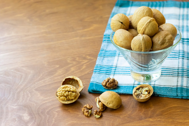 把不带壳的整个核桃和核桃仁切成两半放在深色木桌上，用格子毛巾擦一擦。普通核桃树的种子。微距食物照片近距离观看。图片下载