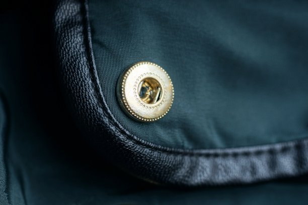 绿色服装面料上的黄色金属铆钉图片下载