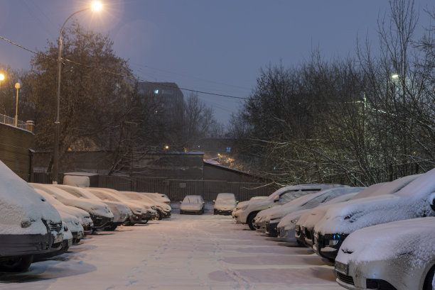 在一场大雪中，停在公寓楼附近的汽车被雪覆盖了。图片下载