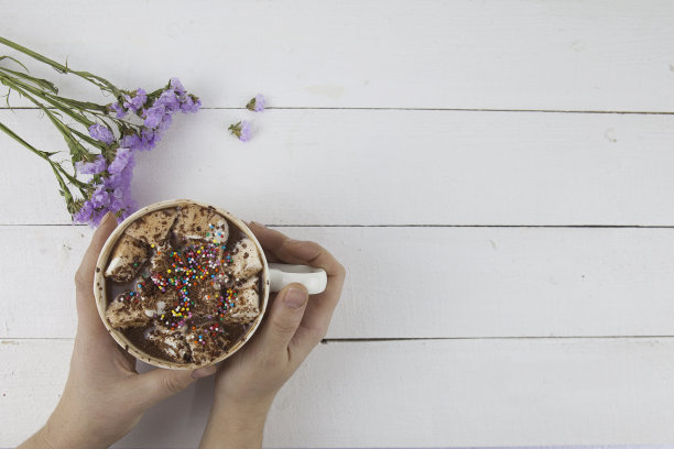 漂亮的照片，女性的手拿着饮料与棉花糖与鲜花图片下载