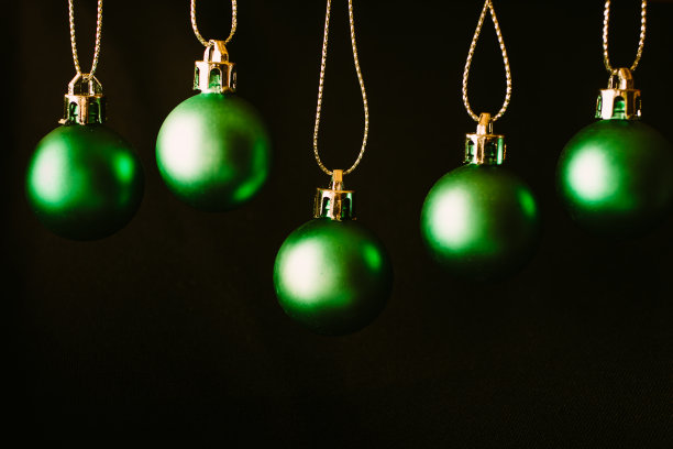 绿色圣诞球的特写视图挂在黑色背景与复制空间。圣诞背景设计。图片下载