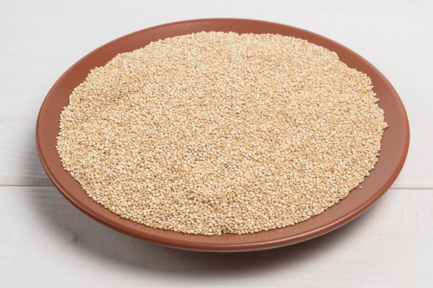 白色木桌上棕色盘子里的藜麦。图片下载