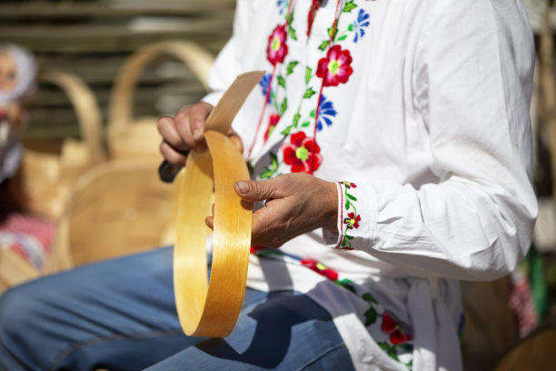 一名身穿刺绣衬衫的斯拉夫男子用桦树皮制作产品。图片下载