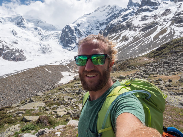 徒步男在远处的山脉、冰川中自拍图片下载