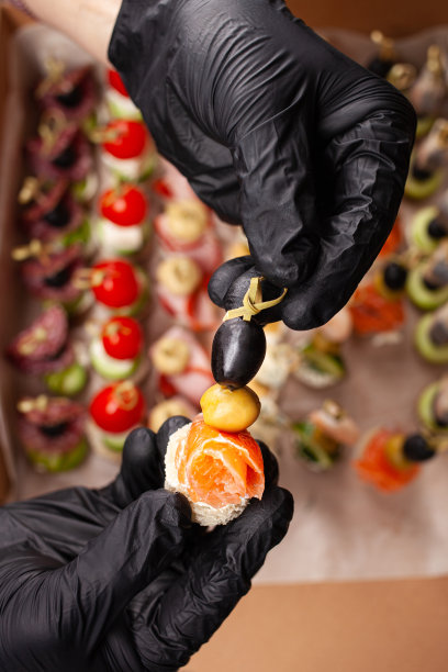 小菜一碟，手在黑色手套拿一个漂亮的小菜一碟在帽子上。工作室的照片。图片下载