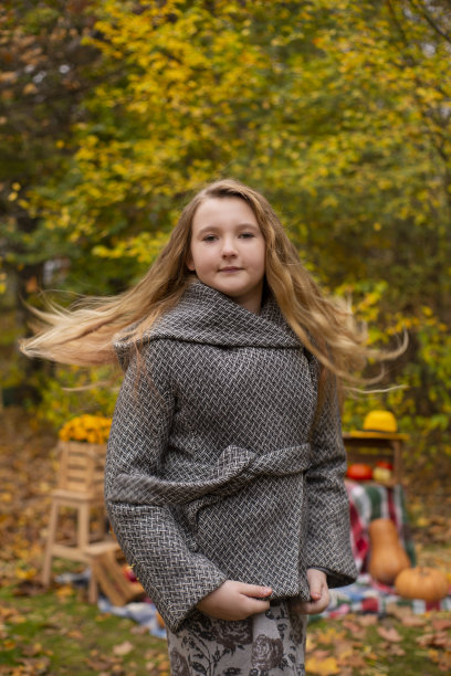 可爱的黑发少女在灰色外套接近秋天元素装饰-南瓜，苹果，格子，干草。舒适,秋天图片下载