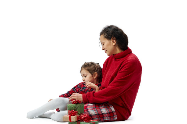 孤立的肖像上的白色。一个年轻的女人坐在地板上拥抱她的女儿。附近是圣诞礼物。图片下载