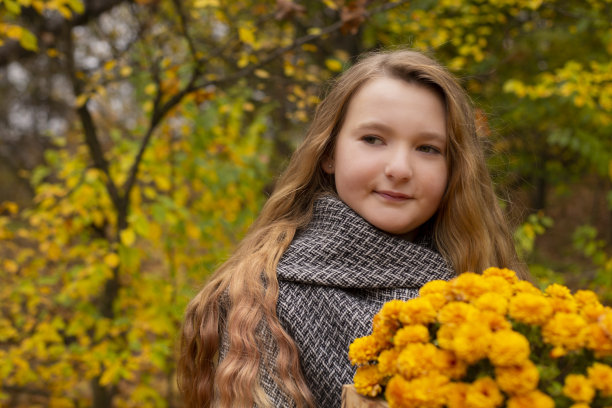可爱的褐发少女穿着灰色外套拿着一个木制的花篮。舒适,秋天图片下载