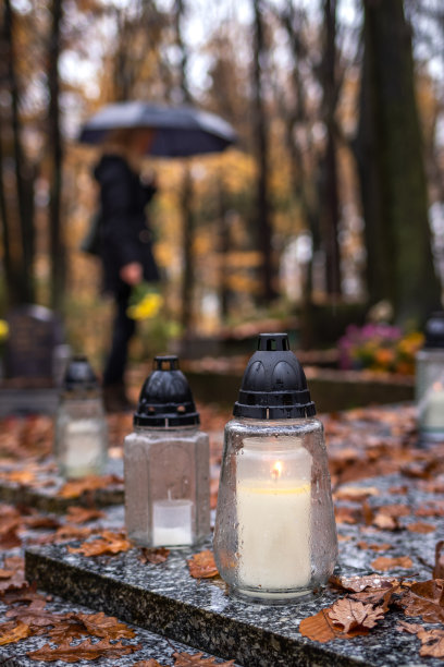墓前的烛灯。在模糊的墓地里哀悼的女人图片下载