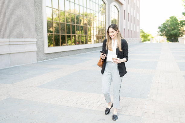面带微笑的职业女性，拿着咖啡和智能手机去上班图片下载