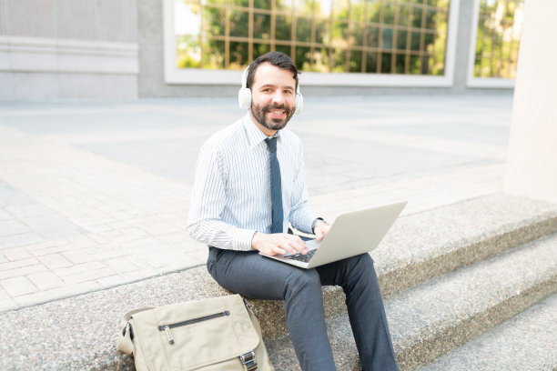 一个快乐的商人戴着耳机在电脑前工作的肖像图片下载