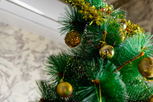 绿色人造圣诞树上的金色圣诞装饰。让圣诞节充满节日气氛。有趣可爱的玩具和礼物图片下载