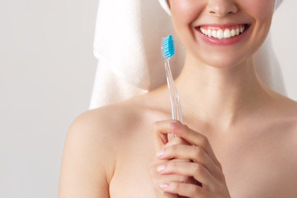 美丽微笑的女人清洁她的牙齿用牙刷在牙科卫生的概念。孤立在白色图片下载
