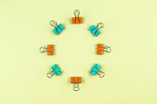 文具套，多色回形针排成圆形，平铺黄色背景，复制空间图片下载