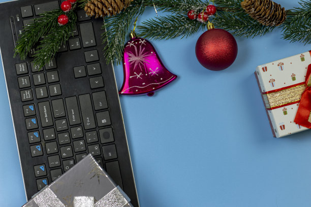 装饰圣诞组成。一台电脑，一个礼品盒，一个云杉树枝，还有圣诞装饰品。图片下载