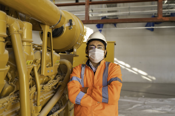 年轻的男工程师微笑着站在他工作的工厂的一台机器前图片下载