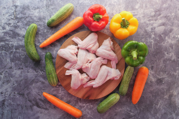 餐桌上有生鸡翅和蔬菜。图片下载