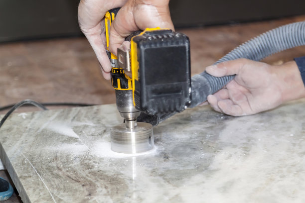 勤杂工用手钻在厨房的大理石台面上凿出圆形的插座孔图片下载