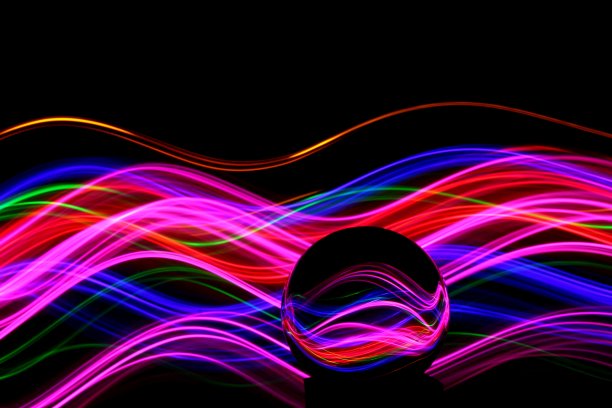 长时间曝光的霓虹灯照片，在一个抽象的漩涡，平行的线条模式与黑色的背景反射在一个玻璃球球。光绘摄影。图片下载