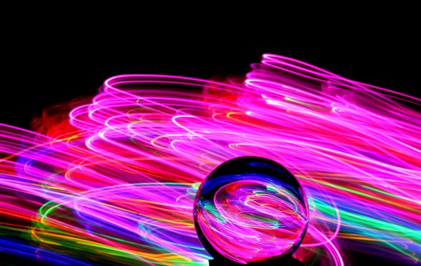 长时间曝光的霓虹灯照片，在一个抽象的漩涡，平行的线条模式与黑色的背景反射在一个玻璃球球。光绘摄影。图片下载