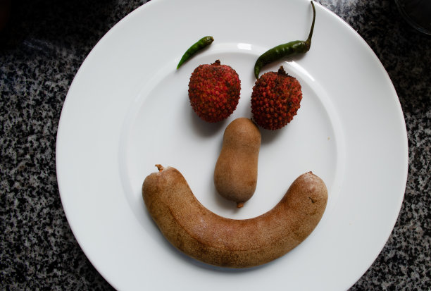 荔枝，辣椒和狨猴在盘子里。由食物做成的滑稽笑脸图片下载