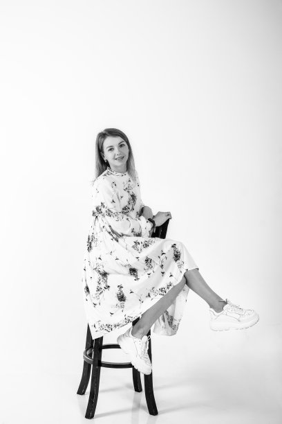 一个漂亮的年轻女子倚在椅子上的肖像。灰色背景上的摄影工作室图片下载