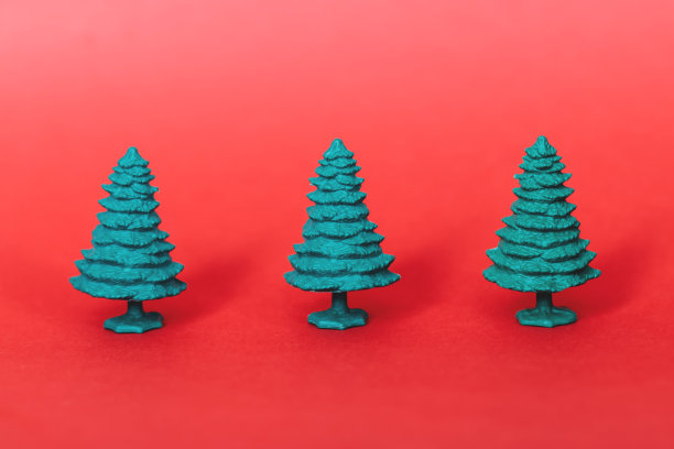 红色背景上的绿色塑料圣诞树。图片下载