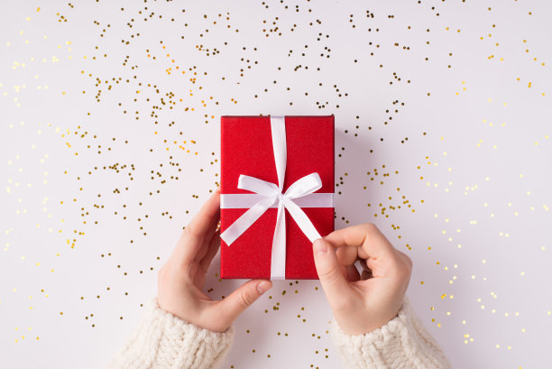 近距离观察上面的pov头顶上的照片，女性的手打开礼物的白色丝带在白色与金色闪闪发光图片下载