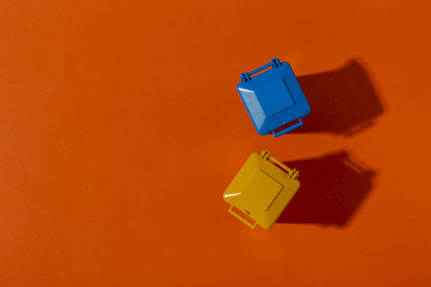 蓝色和黄色的垃圾桶在橙色的背景。清洁的概念。图片下载