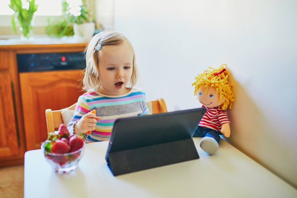 可爱的蹒跚学步的小女孩吃新鲜草莓和使用药片图片下载