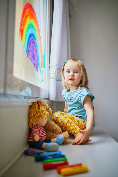 可爱的小女孩在窗户玻璃上画彩虹图片下载