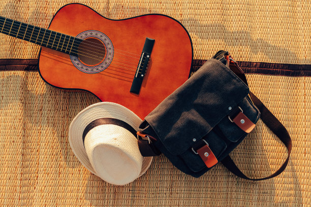帽子，包和吉他在芦苇席子在海边日落。旅游、度假、度假、避暑概念。图片下载