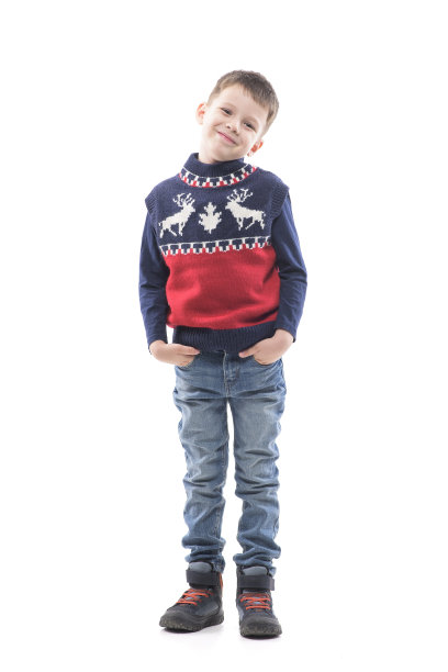可爱的凉爽的年轻男孩孩子在圣诞节毛衣与手在口袋对着镜头微笑。图片下载