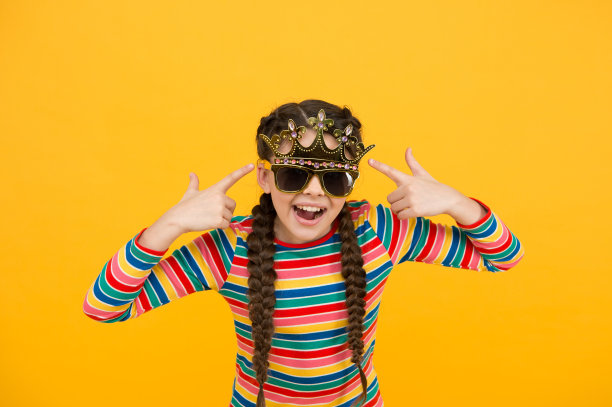 她应得的冠冕。快乐的女孩指着道具王冠和眼镜。小小姐得到了奖励。选美皇冠的灵感。皇冠。时尚配件。金色的王冠或头饰。“大老板”图片下载