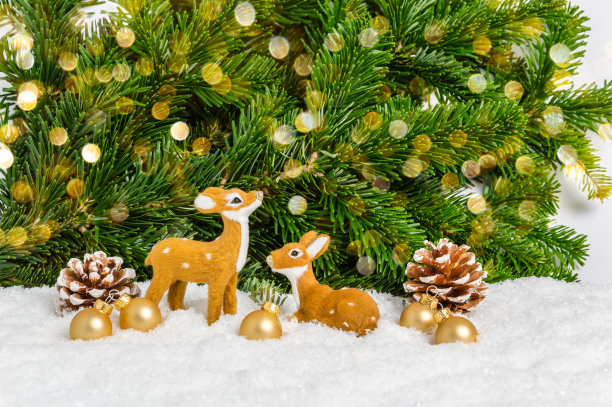 两个圣诞驯鹿和金球在雪与松树和散焦作为背景。节日贺卡。圣诞快乐，恭贺新禧图片下载