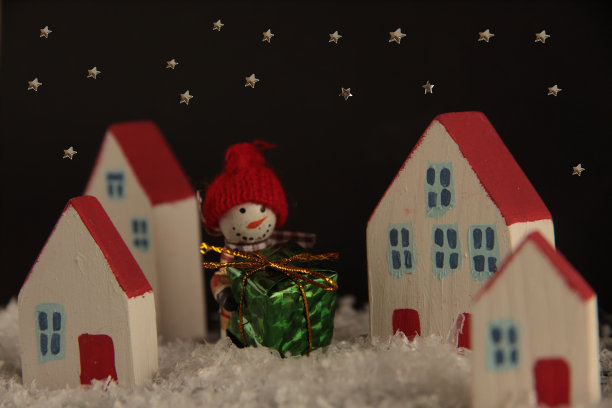 雪人带着礼物走在夜晚的城市近处，星星在黑色的天空。圣诞节的概念图片下载