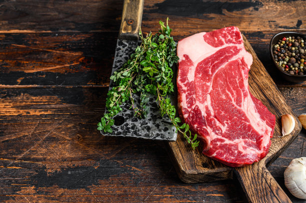 生黑安格斯上等牛肉卷牛排在切板与切肉刀。深色木制背景。前视图。本空间图片下载