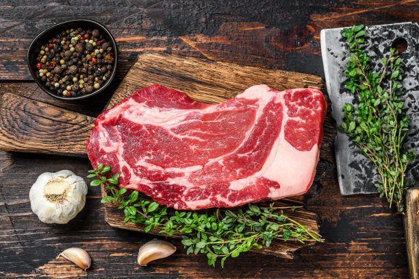 生黑安格斯上等牛肉卷牛排在切板与切肉刀。深色木制背景。俯视图图片下载