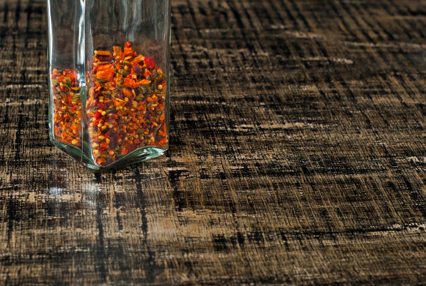 各种香料的混合物在一个玻璃罐中闭合。在一块又黑又旧的木板上放着香料和调味品。免费空间和复制空间的文本附近的调味品。图片下载