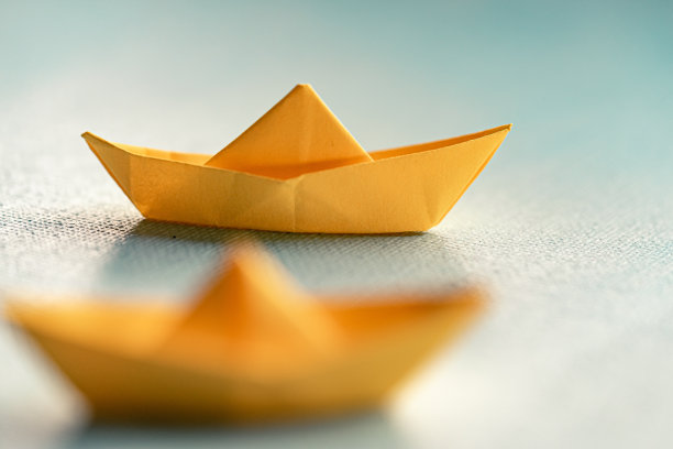 用蓝色纸在海上折纸的黄色帆船。纸张艺术风格的背景与船和海洋图片下载