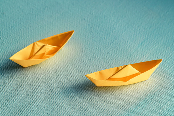 用蓝色纸在海上折纸的黄色帆船。纸张艺术风格的背景与船和海洋。顶视图拍摄图片下载