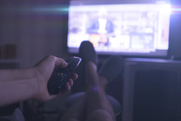 人躺在家里看电视，把腿放在桌子上，享受和放松图片下载