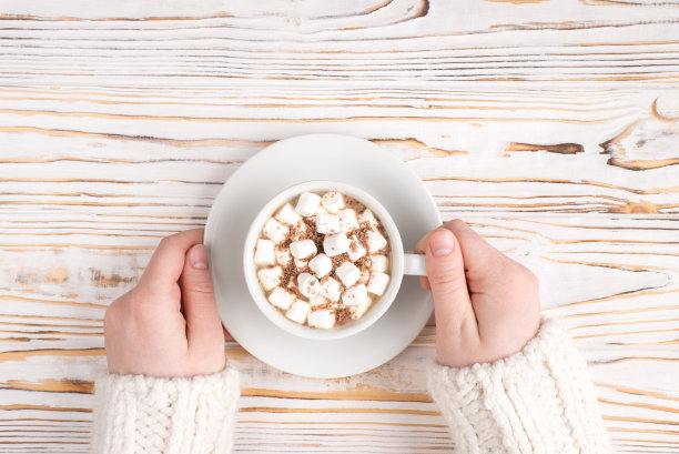 Pov顶部在头顶上近距离观看照片的女性的手拿着一杯可口的饮料与软糖棉花糖在木制的背景图片下载