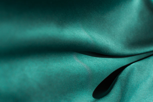 绿色缎面织物褶皱特写。抽象趋势背景的2021潮水绿色颜色素材图片