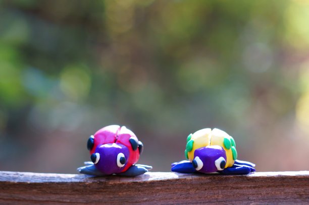 两个用橡皮泥制成的瓢虫在森林里的彩色背景。图片下载