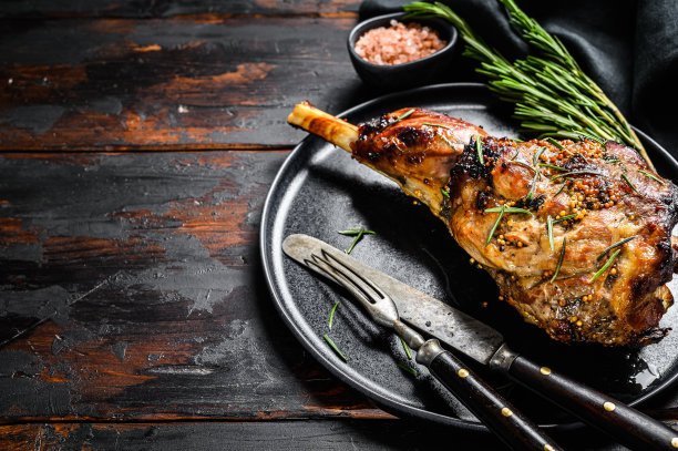 烤羊肉，迷迭香羊腿。深色木制背景。前视图。本空间图片下载